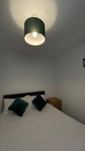 Un dormitorio con una cama blanca con una luz en el techo en M6 Jct 10, 2 Bed House Wolverhampton-Walsall en Willenhall