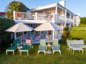 a group of chairs and umbrellas in front of a house at Southern Cross Beach House in Plettenberg Bay