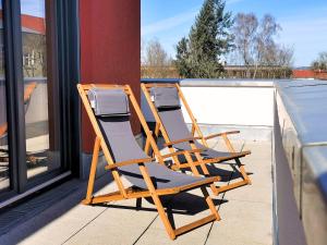 three lounge chairs sitting on a balcony next to a pool at Fynbos City Penthouse, Dachterrasse, Design-Küche, Parkplatz in Straubing