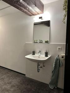 a white bathroom with a sink and a mirror at PrimeBnb Bad Hersfeld in Bad Hersfeld