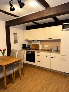 a kitchen with white cabinets and a wooden table at PrimeBnb Bad Hersfeld in Bad Hersfeld