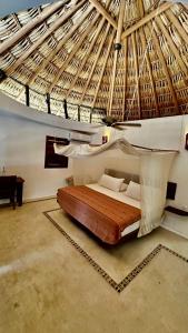 a bed in a room with a straw roof at El Alquimista Yoga Spa in Zipolite