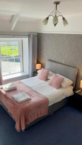 a bedroom with a large bed with pink pillows at Blue Bell Inn in Embleton