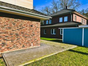 a house with a brick wall and a blue garage at FeWo am Tillysee in Wardenburg in Wardenburg