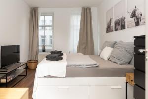 a white bedroom with a large bed and a television at City Apartment am Zoo & Stadtkern in Leipzig