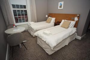 a hotel room with two beds and a table and a window at Five Glens Inn in Manorhamilton