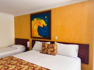 una camera d'albergo con due letti e un dipinto di un cavallo di Hotel Luxor Pereira a Pereira
