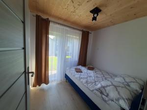 a small bedroom with a bed and a window at Domki Fio in Sarbinowo