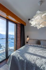1 dormitorio con 1 cama y balcón con vistas. en Gudauri Mountain Views, en Gudauri