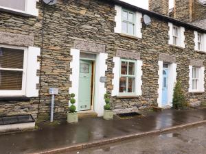 a stone house with a blue door and two plants at Charlottes Cottage in Windermere