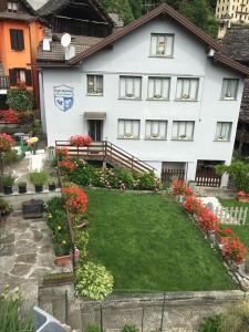 una gran casa blanca con un patio con flores en Casa Vacanza PIZZO CAMINO, en Calasca Castiglione