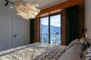 a bedroom with a bed and a balcony with a view at Gudauri Mountain Views in Gudauri