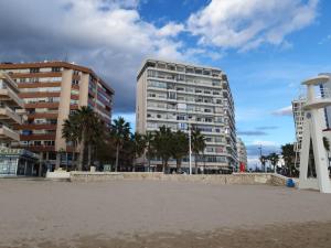 a building on the beach with palm trees and buildings at Apartamento Mar y Paz 15 in Calpe