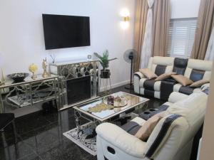 Luxurious Five-Bedroom Haven في Long Stanton: غرفة معيشة مع كنبتين وتلفزيون