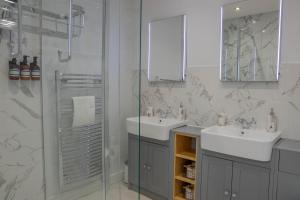 a bathroom with two sinks and a glass shower at Bridgeside Rooms in Ironbridge