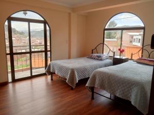 two beds in a room with two large windows at Villa Bella Copacabana in Copacabana