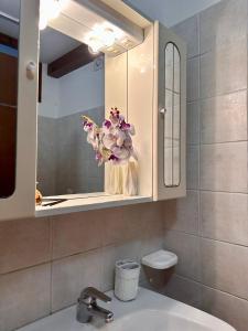 a bathroom with a sink and a vase of flowers at Affittacamere La Dimora dei Nonni in Cascia