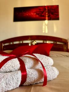 uma pilha de toalhas com uma fita vermelha numa cama em Affittacamere La Dimora dei Nonni em Cascia