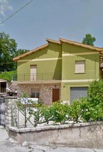 una casa verde lima con una pared de piedra en Affittacamere La Dimora dei Nonni, en Cascia