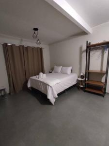 ein Schlafzimmer mit einem großen Bett mit weißer Bettwäsche und Kissen in der Unterkunft TEMPO FLATS E HOSPEDAGEM in Alto Paraíso de Goiás