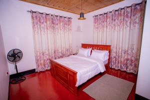 a bedroom with a bed and curtains and a fan at Royal Homestay in Moshi