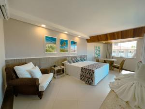 a bedroom with a bed and a couch and chairs at Hotel Aldeia da Praia in Ilhéus