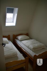 two twin beds in a room with a window at InBuren in Buren