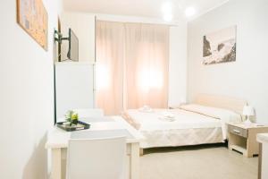 a small white room with a bed and a desk at Rael in Cefalù