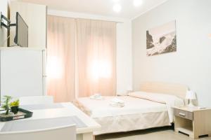 a white bedroom with a bed and a desk at Rael in Cefalù