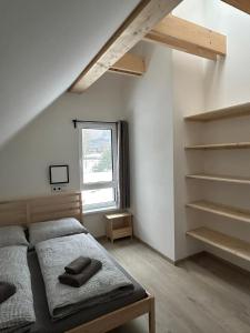 a bedroom with a bed and a window and shelves at Horský dům Vojta in Rokytnice nad Jizerou