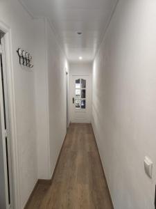 un corridoio con pareti bianche e pavimento in legno di Habitación acogedora matrimonial a Olesa de Montserrat