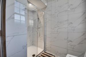 a shower with marble walls and a glass door at Orrell Apartment with free parking in Upholland