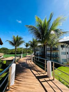 une passerelle avec des palmiers et un bâtiment dans l'établissement Hotel Aldeia da Praia, à Ilhéus