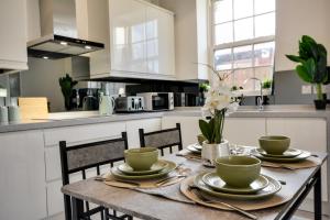 a kitchen with a table with plates and bowls on it at Orrell Apartment with free parking in Upholland