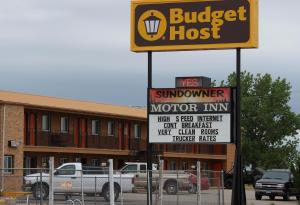 a sign in front of a building with a truck at Budget Host Sundowner Motor Inn Kadoka in Kadoka