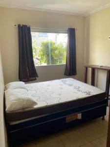 Ce lit se trouve dans un dortoir doté d'une fenêtre. dans l'établissement Apartamento próximo Arena Axé Moi, à Porto Seguro