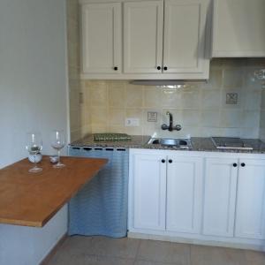 a kitchen with white cabinets and a sink and two wine glasses at Es Niuet in Cala Galdana