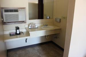 La salle de bains est pourvue d'un lavabo et d'un miroir. dans l'établissement Budget Host Sundowner Motor Inn Kadoka, à Kadoka