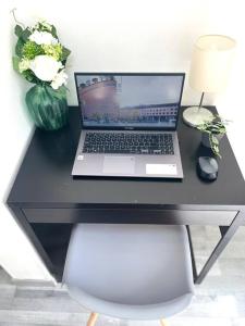 a laptop computer on a black desk with a vase of flowers at Hypercentre Evry Appartement équipé avec Parking inclus in Courcouronnes
