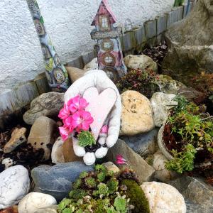 a heart shaped rock with a bird house and flowers at Hannis Appartement in Erkelenz