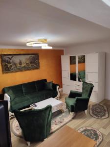 a living room with a green couch and two chairs at Casa de pe colt in Alba Iulia