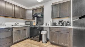 una cocina con armarios de madera y electrodomésticos de acero inoxidable en Modern Corporate 2br Suite Pool, Gym Pp, en Harrisburg