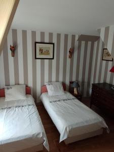 twee bedden in een kamer met gestreepte muren bij Maison de campagne in Ambleny