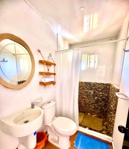 a bathroom with a toilet and a sink and a mirror at Tayrona Angel Lodge in El Zaino