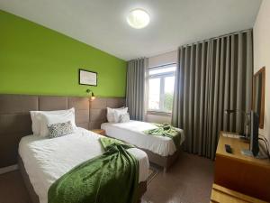 a hotel room with two beds and a green wall at Hospedaria Verdemar in Horta
