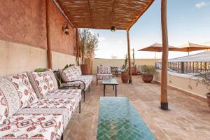 a patio with couches and a table and an umbrella at Riad Amalia in Marrakech