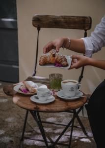 Eine Person hält einen Teller mit Essen auf einem Tisch mit Tassen. in der Unterkunft Maharìa in Menfi