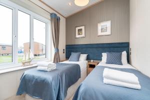 2 Betten in einem Zimmer mit 2 Fenstern in der Unterkunft Stewarts Resort Lodge 18 in St Andrews