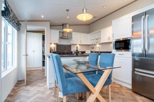 a kitchen with a glass table and blue chairs at Stewarts Resort Lodge 18 in St Andrews