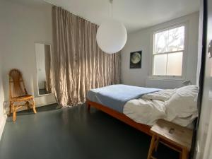 a bedroom with a bed and a window and a chair at Bright and peaceful mews flat in London